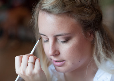 Bride getting makeup by window at Adam's Pond