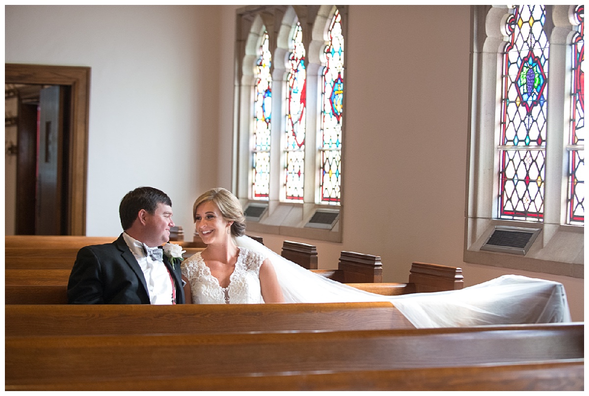 bride and groom in church by stained glass windows